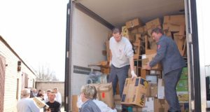 Estenfeldo maltiečiai iškrauna atgabentus mokyklinius stalus ir įvairias dovanas vaikams. D.Zibolienės nuotr.