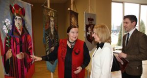 Scenografė S. Kanaverskytė (kairėje) pasakoja apie vėliavų siūvimo rankomis techniką parodos atidaryme dalyvavusiems lankytojams. A. Mackuvienės nuotr.