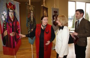 Scenografė S. Kanaverskytė (kairėje) pasakoja apie vėliavų siūvimo rankomis techniką parodos atidaryme dalyvavusiems lankytojams. A. Mackuvienės nuotr.