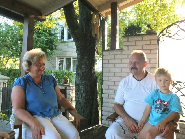 Danguolės ir Aloyzo Jočių šeimos gyvenimas vasarą persikelia į po medžiais skendinčią verandą. Su anūku Adomu. A. Minkevičienės nuotr.