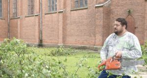 Kamajų klebonas Raimondas Kazlauskas pats šventoriuje pradėjo pjauti nulūžusios liepos šakas. D.Zibolienės nuotr.