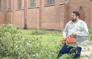 Gamtos stichija vartė medžius, plėšė stogus Kamajų klebonas Raimondas Kazlauskas pats šventoriuje pradėjo pjauti nulūžusios liepos šakas. D.Zibolienės nuotr.