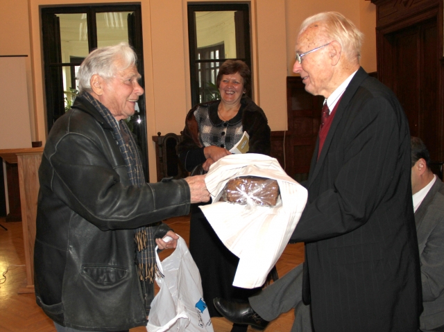 Ūkininkų sąjungos pirmininkas Vytautas Šlikas (kairėje) dovanojo akademikui Leonardui Kairiūkščiui rajono žemdirbių užaugintą ir iškeptą duoną. Viduryje - renginio vedėja Krašto muziejaus direktorė Nijolė Šniokienė. D.Zibolienės nuotr.