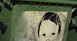 Ant konteinerių su vaiko atvaizdu šviečia užrašas SAGE: galbūt tai – grafičio autoriaus slapyvardis ar kūrinio pavadinimas.