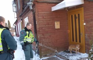 Valkataujantis šuo užtvėrė kelią į namus Policijos pareigūnai Romas Navikas (kairėje) ir Henrikas Siniauskas bandė pagaliu nuo durų nuvyti šunį.